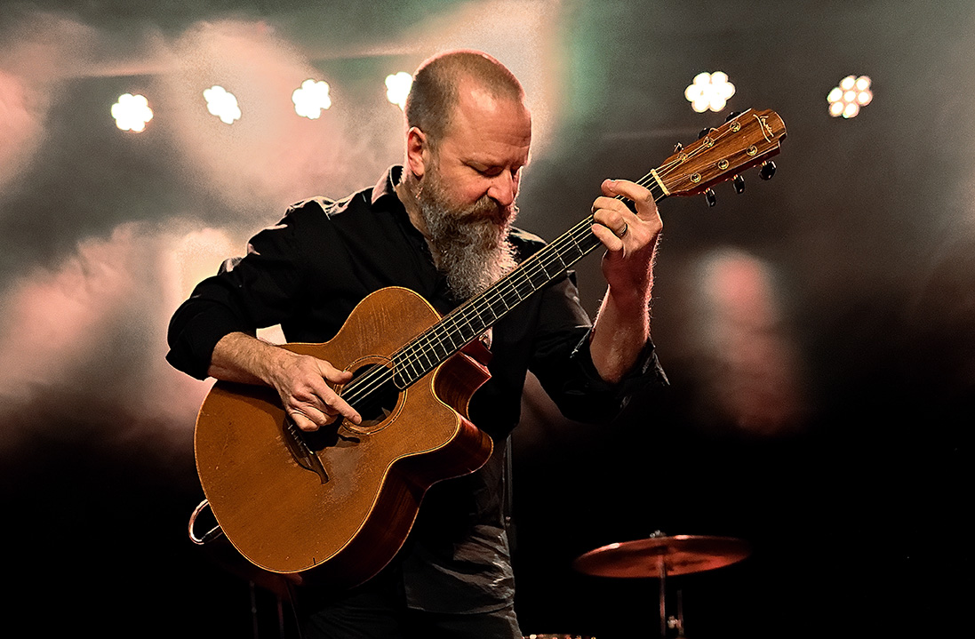 Jeff Aug performing live on stage with guitar